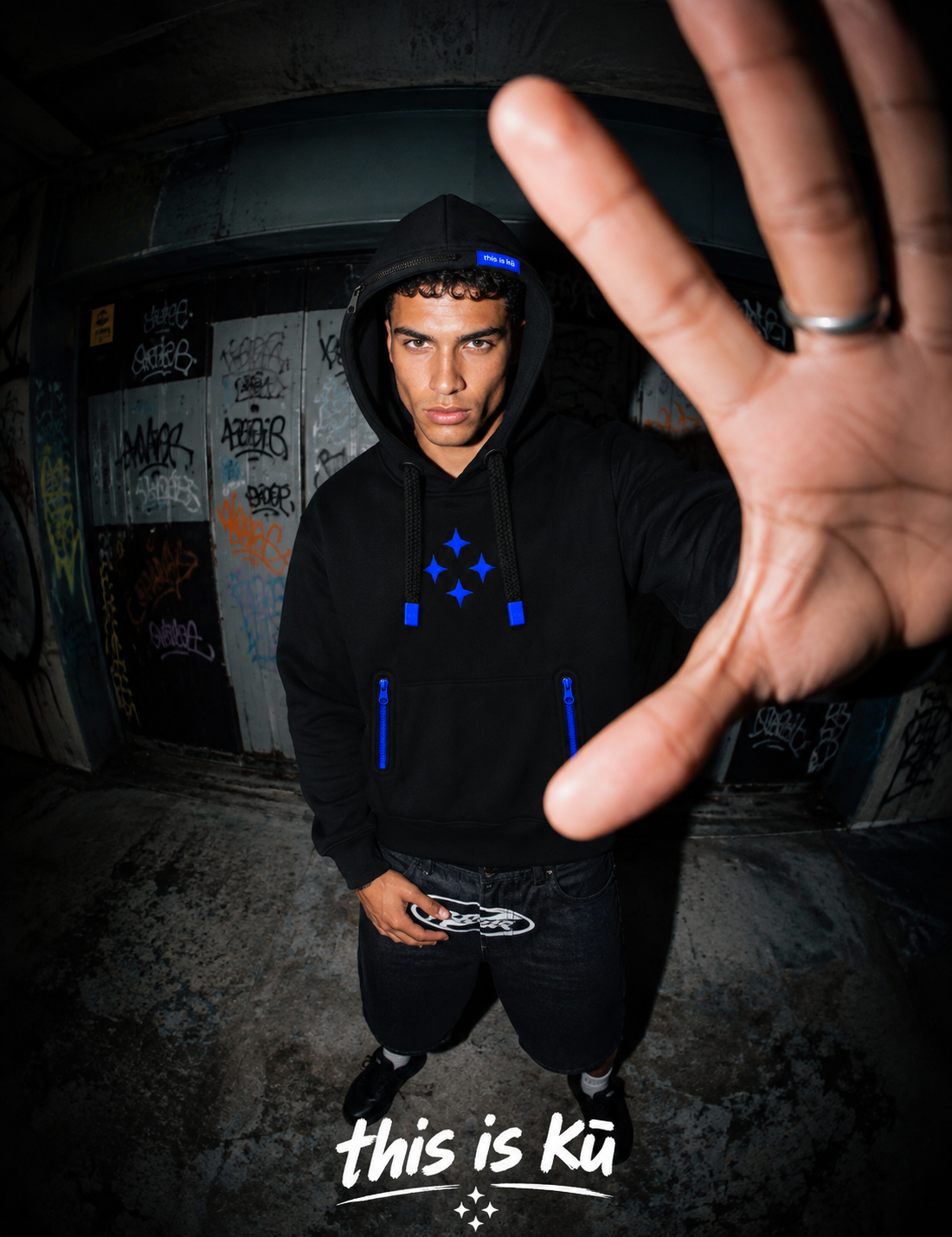 Modelo con la sudadera negra Kū Star Hoodie en un entorno urbano